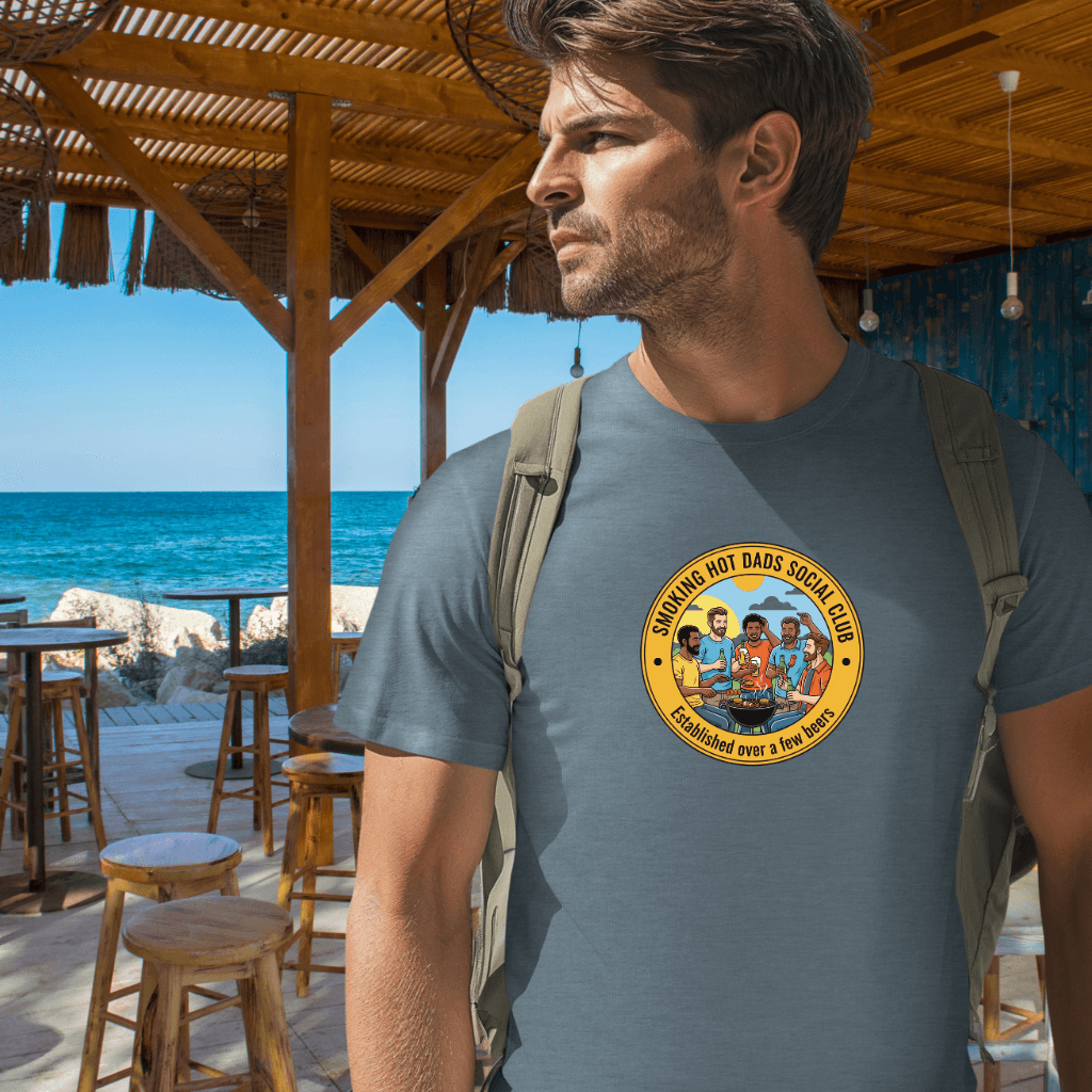 Man wearing a Smoking Hot Dads Social Club t-shirt with a logo at a beachside bar